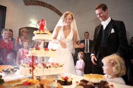 Ein Brautpaar schneidet eine 3 stöckige Hochzeitstorte an.