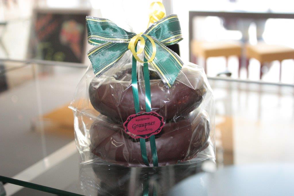 1 Baumkuchen mit 2 Ringen in Folie eingepackt und mit einer grünen Schleife verziert