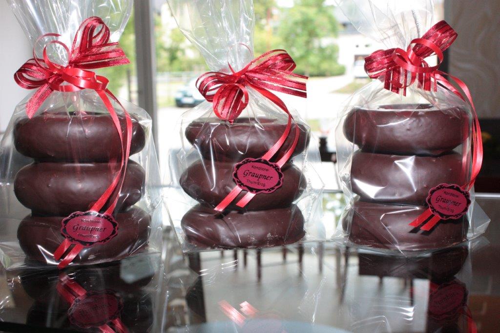 3 Baumkuchen mit jeweils 3 Ringen in Folie eingepackt und mit weinroten Schleifen verziert